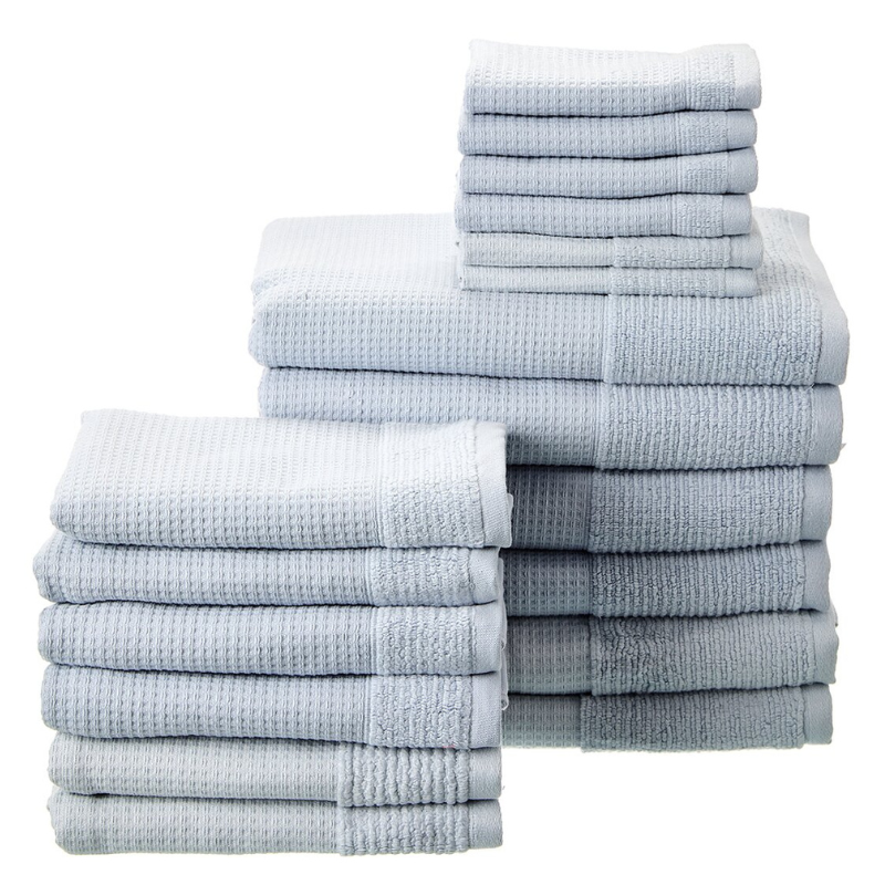 A set of neatly stacked light gray towels, including different sizes for various uses, arranged in two main piles.