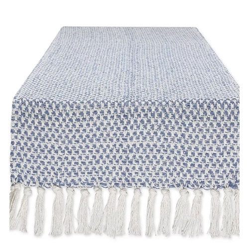 A woven table runner featuring a blue and white checkered pattern with tassels at the ends.