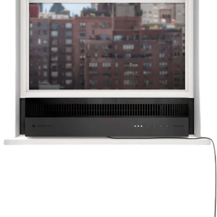 A window-mounted air conditioner with a sleek black design and minimal controls on the front panel, set against an urban background.