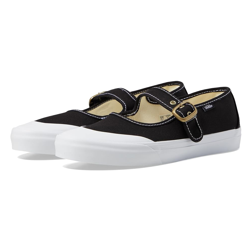 Black Vans Mary Janes with a white rubber sole, featuring a canvas upper and a buckle strap across the top. Accented with white stitching for added detail.