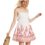 A woman wears a sleeveless white dress with red floral patterns, holding a woven straw bag.