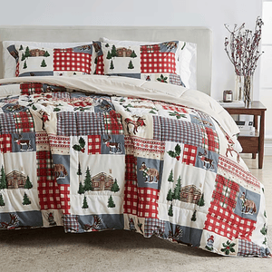 A patchwork quilt set featuring rustic designs with cabins, animals, and plaid patterns in red, blue, and beige tones; includes a comforter and matching pillow shams.