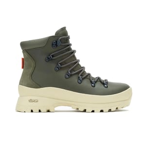 A green hiking boot with a beige Vibram sole, featuring black laces and metal eyelets.