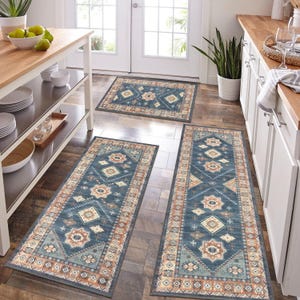 3-piece kitchen rug set featuring a southwestern geometric pattern in blue, beige, and rust colors on a dark wood floor. Includes a small mat, and two long runners placed near countertops and a kitchen island.