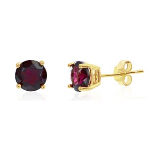 Gold stud earrings featuring deep red garnet gemstones set in four prongs, with butterfly backings for secure wear.