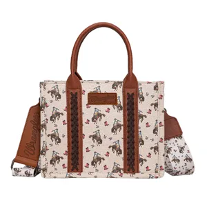 A beige tote bag with brown leather accents featuring a cowboy and horse pattern, and \“Wrangler\“ branding on the bag and detachable shoulder strap.