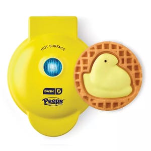 A yellow Dash waffle maker with Peeps branding sits next to a waffle featuring a chick design.