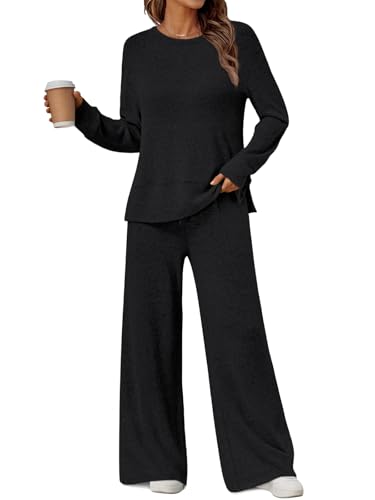 A woman is wearing a black, two-piece lounge set with long sleeves and wide-legged pants, paired with white sneakers. She is holding a coffee cup in her right hand.