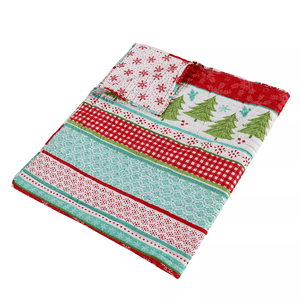 A Christmas-themed quilt with festive patterns including snowflakes, Christmas trees, and red and green stripes.