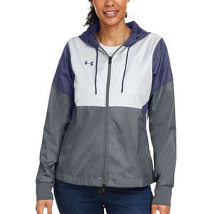 A woman wearing a color-blocked hooded jacket with shades of purple, white, and gray, featuring a small logo on the chest, paired with blue jeans.