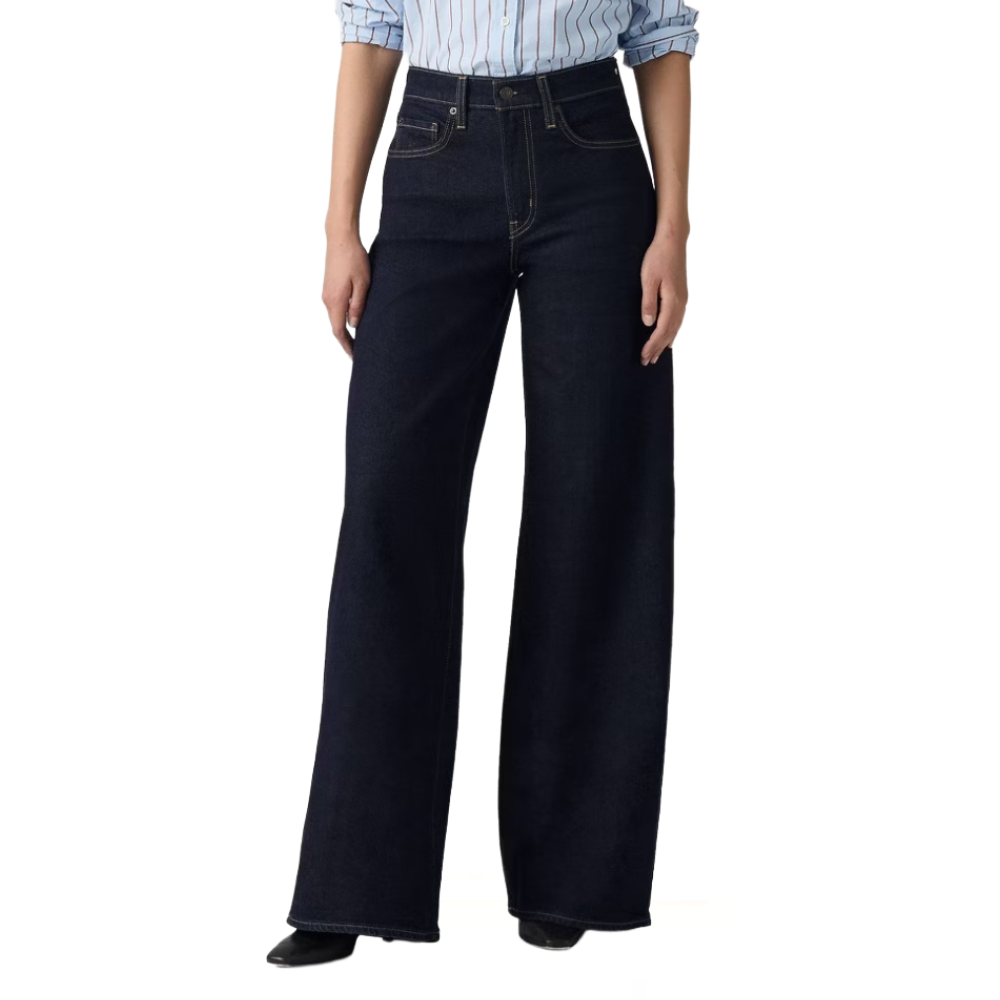A person is wearing high-waisted, dark wash, wide-leg jeans paired with a light blue pinstriped shirt.