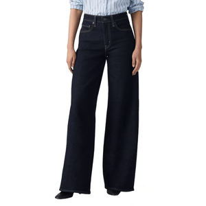 A person is wearing high-waisted, dark wash, wide-leg jeans paired with a light blue pinstriped shirt.