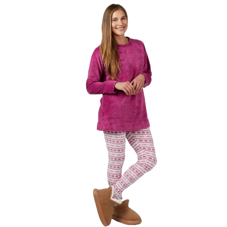 A woman stands smiling, wearing a pink sweatshirt, patterned leggings, and brown boots.