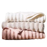 Three stacked towels in shades of white, beige, and pink.