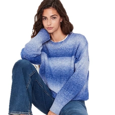 A woman is wearing a blue ombre crew-neck sweater with a relaxed fit and long sleeves, paired with casual denim jeans.