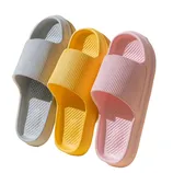 Three pairs of slide sandals in gray, yellow, and pink with a ribbed strap design and textured footbed.