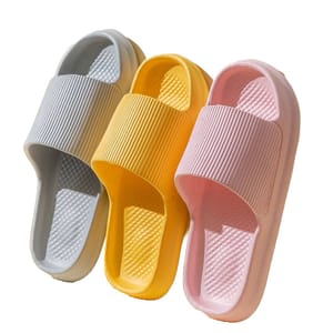 Three pairs of slide sandals in gray, yellow, and pink with a ribbed strap design and textured footbed.
