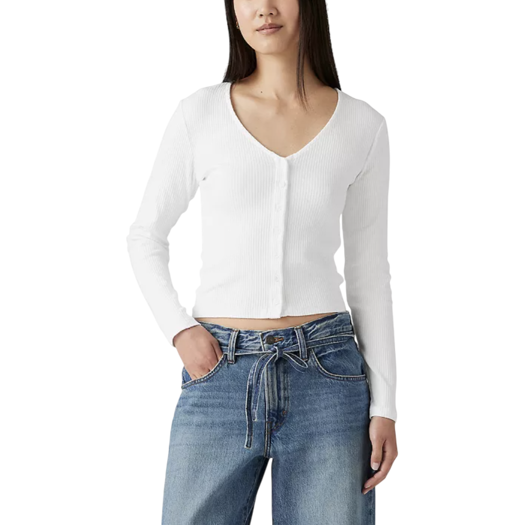 A woman wears a white ribbed V-neck button-up long-sleeve top paired with blue high-waisted wide-leg jeans that feature a tie belt.