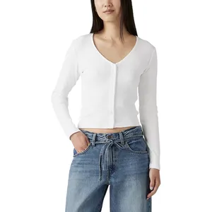 A woman wears a white ribbed V-neck button-up long-sleeve top paired with blue high-waisted wide-leg jeans that feature a tie belt.
