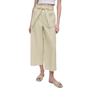 Beige paperbag waist cropped pants with a tie belt, paired with a white crop top and beige slip-on sandals.