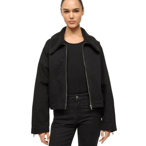 A person is wearing a black jacket with a sherpa collar over a black ribbed shirt and matching black pants.