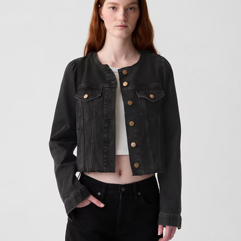A collarless, cropped denim jacket with flap pockets and contrasting button fastenings on the front.