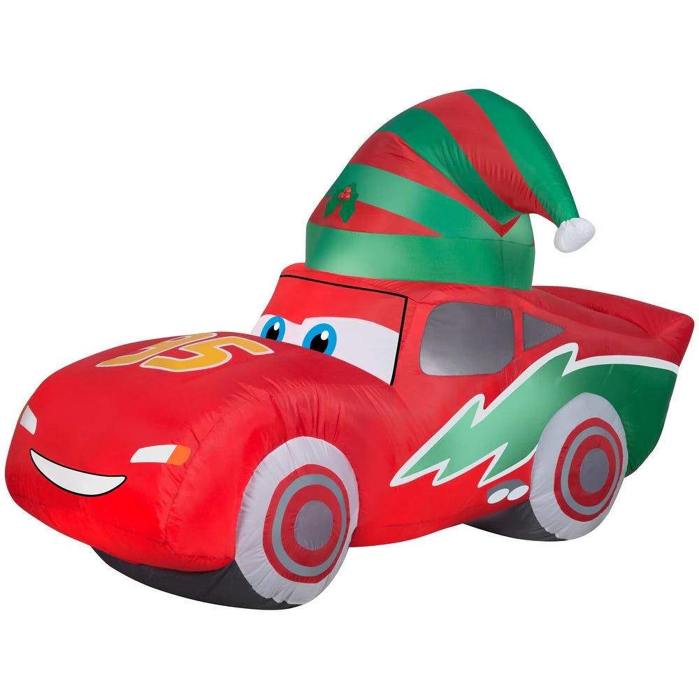 Inflatable car decoration featuring a red racing car with large eyes and a Christmas elf hat, decorated for the holiday season.