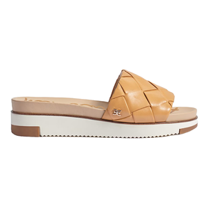 Tan woven leather slide sandal with a low wedge sole and contrast white platform. Features a small decorative emblem on the strap.