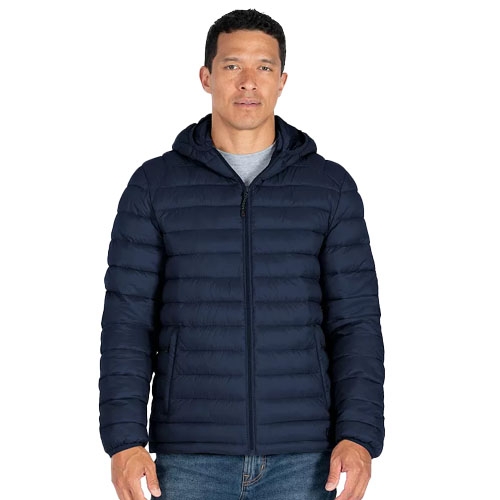 A man wears a dark blue, quilted puffer jacket with a hood over a gray shirt and blue jeans.