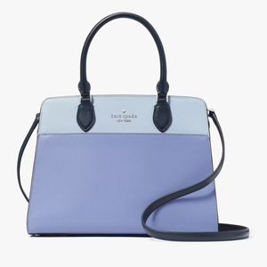 A two-toned blue Kate Spade handbag with black handles and a detachable strap.