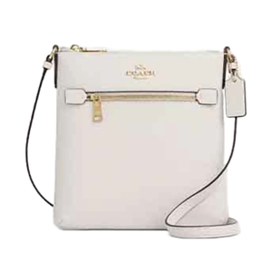 A compact white crossbody bag with a front zip pocket, gold-tone hardware, and an adjustable strap. The Coach logo is embossed on the front and a matching tag hangs from the side.