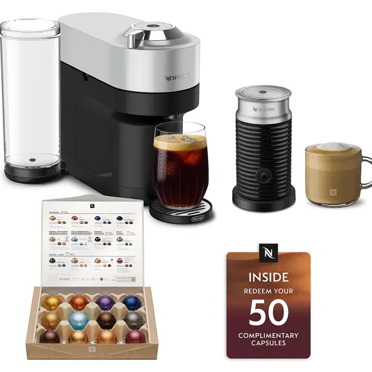 Nespresso coffee maker with a frother, two prepared drinks, a variety box of capsules, and a card offering redemption for 50 complimentary capsules.