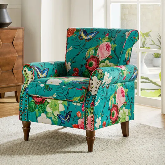 A colorful floral and butterfly patterned armchair with nailhead accents on arms and wooden legs.
