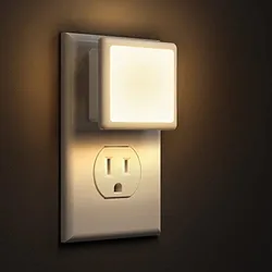 A plug-in night light with a square, soft-glow design attached to a wall outlet, suitable for ambient lighting.