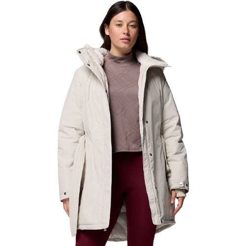 A woman is wearing a light-colored winter coat with a high collar over a mauve turtleneck and maroon leggings.