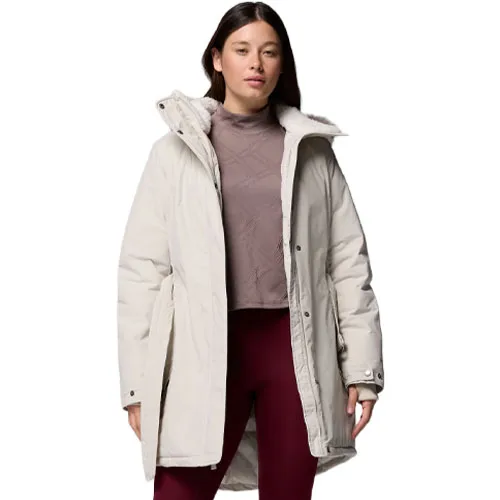 A woman is wearing a light-colored winter coat with a high collar over a mauve turtleneck and maroon leggings.