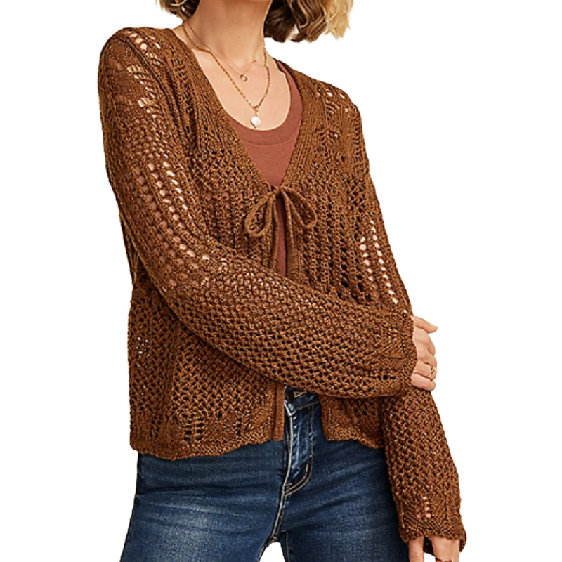 A woman is wearing a brown, open-knit cardigan with a tie front over a brown top, paired with blue jeans.