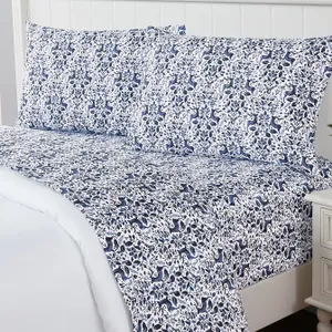 A patterned bedsheet set featuring a blue and white botanical and animal design on a bed with matching pillowcases.