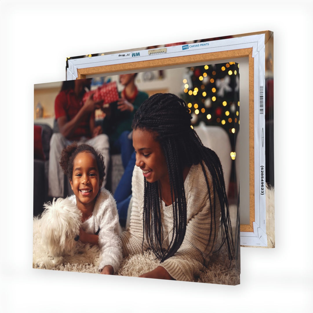 A framed canvas print featuring a joyful scene with two people and a white dog, against a festive background with a Christmas tree.