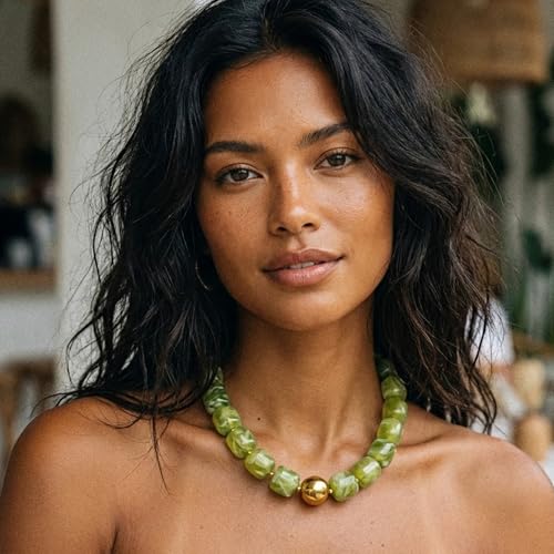 A woman wears a green beaded necklace with a large metallic gold bead at the center.