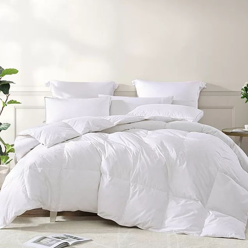 A plush white comforter filled with goose feathers, featuring a quilted design and accompanied by matching white pillows, offers a cozy and luxurious bedding setup.