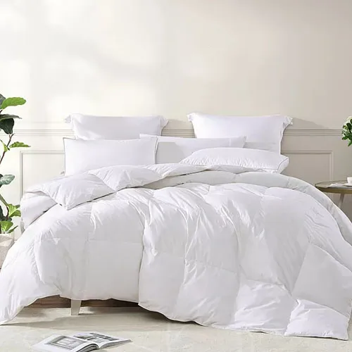 A plush white comforter filled with goose feathers, featuring a quilted design and accompanied by matching white pillows, offers a cozy and luxurious bedding setup.