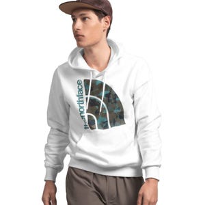 A man is wearing a white hoodie with the North Face logo overlaying a large, partially obscured graphic.
