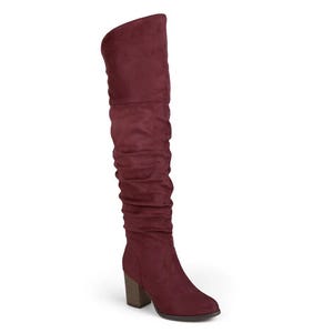 A red knee-high boot with a slouchy design and a chunky wooden heel.
