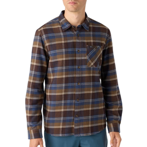 A man is wearing a brown and blue checkered long-sleeve button-up shirt with a chest pocket, paired with teal pants.