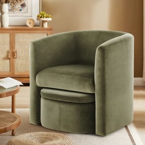 Green upholstered barrel chair with a curved backrest, situated in a cozy room with a wooden cabinet and round table.
