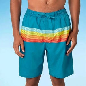 A person wearing blue swim shorts with a horizontal rainbow stripe design.
