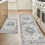 Two kitchen rugs with intricate blue and gray patterns are placed on a light wooden floor, adjacent to wooden cabinets and a white stove.