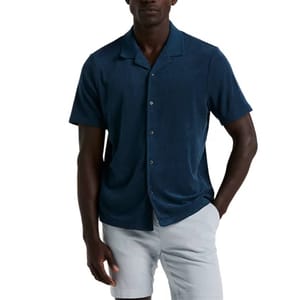 A man wears a dark blue short-sleeve button-up shirt paired with light gray shorts.