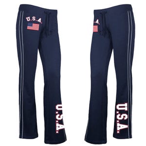 Navy blue women's pants featuring \“U.S.A.\“ in white lettering with red outline, an American flag design on the hip, and vertical stripes on the sides.